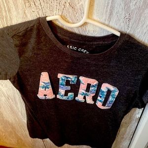 Light grey shirt sleeve T-shirt. Pink with palm trees lettered.
